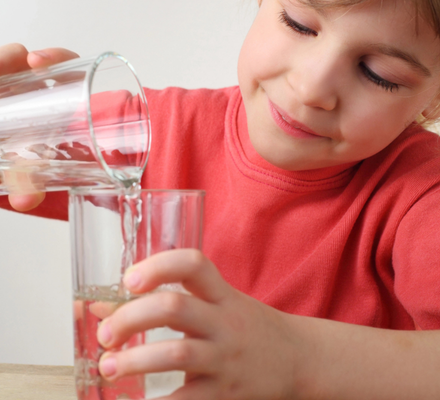 Girl practicing pouring water into a glass