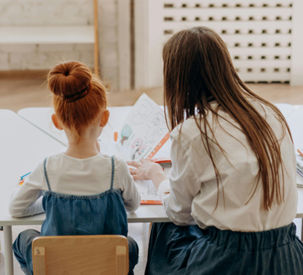Adult and child reviewing a workbook side by side