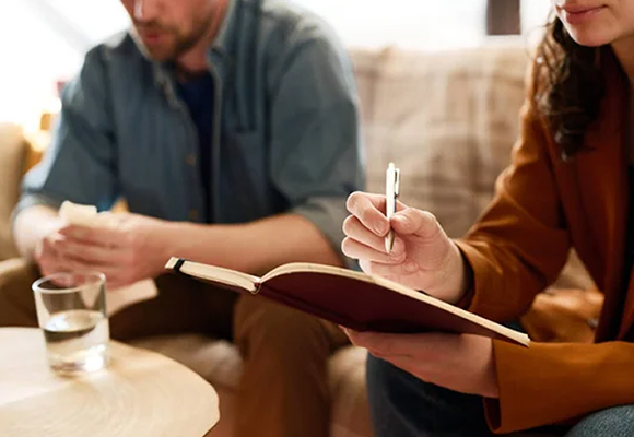 Two people in a discussion with one taking notes